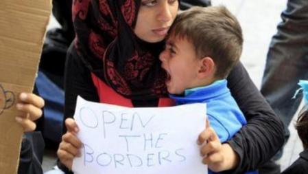 Una mujer siria con un bebé en brazos sostiene un cartel que pide 'Abrid las fronteras' en la estación de Keleti en Budapest