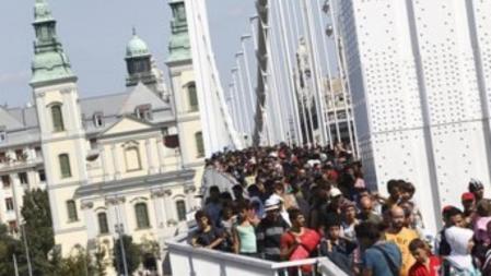 Cientos de inmigrantes cruzan un puente sobre el río Danubio en Budapest al inicio de su marcha hacia Austria