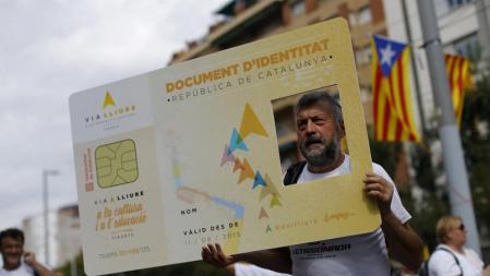 Un hombre con un ejemplo de posible documento de identidad catalán
