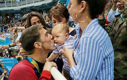 Phelps besa a aus hijo, Boomer, después de una prueba en los Juegos de Rio de 2016&nbsp; (AP Photo/Matt Slocum)
