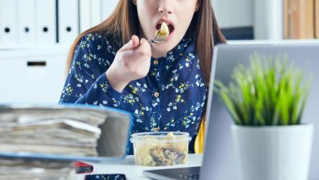 Mujer comiendo su táper en su lugar de trabajo.
