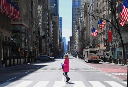 La Quinta Avenida de Nueva York presentaba esta insólita imagen el 27 de marzo con una mujer cruzando un paso de cebra mientras es inapreciable el tráfico por esta importante vía de Manhattan