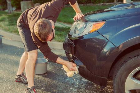 Un hombre limpia el parachoques del coche con una bayeta&nbsp;