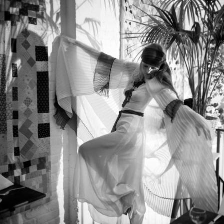 Penny Slinger is seen wearing a blue and white pleated cape over a blue and white embroidered chiffon dress at the Thea Porter show. (Photo by PA Images via Getty Images)