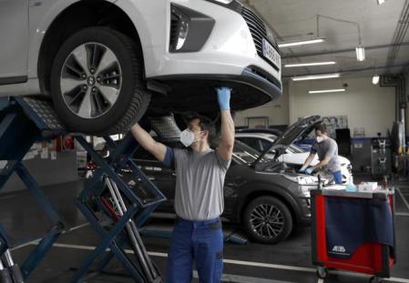 Operarios de un taller revisan el estado de dos coches&nbsp;