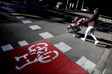 Una joven con un cochecito de bebé cruza una céntrica calle de Barcelona&nbsp;