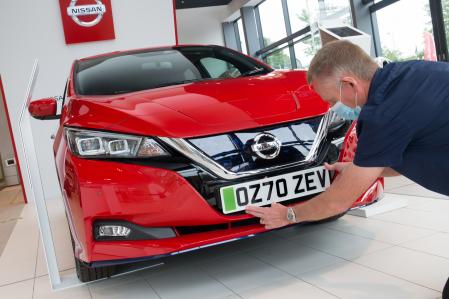 Un operario de un concesionario coloca la nueva placa a un vehículo eléctrico