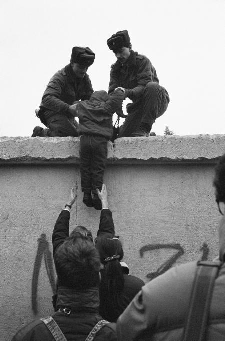 Militares de la República Democrática ayudan a cruzar el muro de Berlín a un niño de la parte occidental