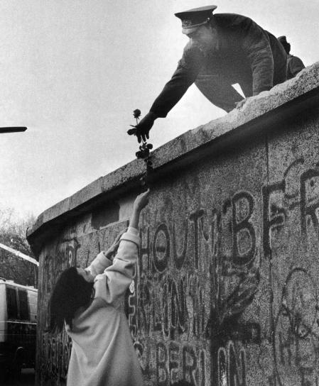 Un militar del Berlín oriental entrega una rosa a una ciudadana occidental antes de la caída del muro