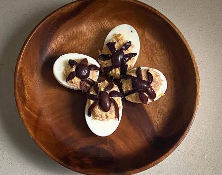 Cortamos finas aceitunas negras y vamos dando forma a arañas encima de cada una de las mitades de los huevos