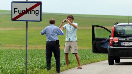 Turistas haciéndose fotos junto al cartel del pueblo de Fucking