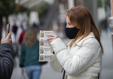 Una persona enseña varios décimos de lotería de Navidad
