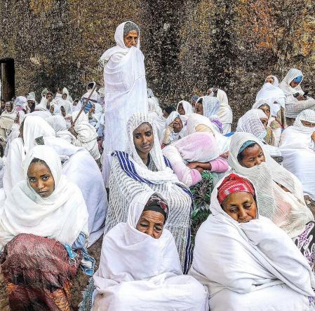 Mujeres agrupadas como ganado rezando.