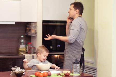 A father talking on the phone while his son playing with dough