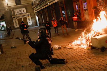 Un policía nacional dispara con un arma a los simpatizatntes del rapero catalán Pablo Hasél, durante las protestas anoche en el centro de Madrid
