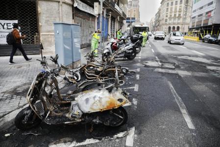 Los operarios de limpieza en la calle Balmes, donde varias motos fueron quemadas durante los altercados en las protestas por la liberación de Hasél