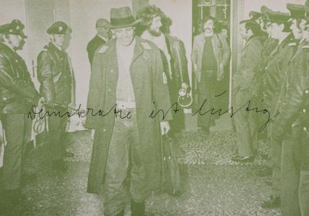 Joseph Beuys, en una fotografia de 1972, sale escoltado por la policia de la Escuela Superior de Bellas Artes de Hamburgo, que ocupó con un centenar de estudiantes en protesta por una decisión del rector. Escrito se lee: 