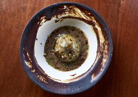 La alcachofa confitada con sopa de butifarra negra y trocitos de jamón