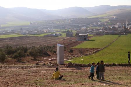 Niños turcos juegan cerca de un monolito metálico con una escritura del alfabeto Gokturk que significa 'Si quieres ver la luna, mira el cielo' que apareció el 05 de febrero en la provincia sureste de Turquía de Sanliurfa, Turquía
