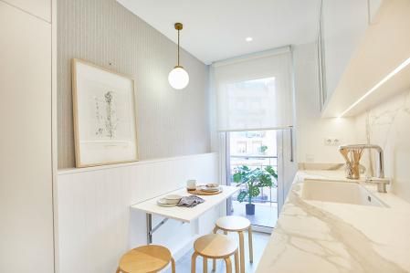 En esta cocina tan estrecha consiguieron desplegar un 'office', con una mesa que queda escondida en el panel de la pared