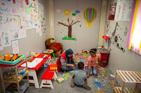 Una mujer juega con dos niños en una actividad de Save the Children.