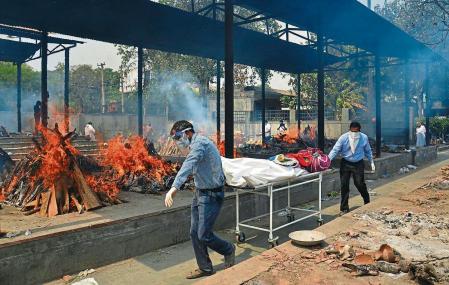 Relatives carry the body of a person who died of COVID-19 as multiple pyres of other COVID-19 victims burn at a crematorium in New Delhi, India, Saturday, May 1, 2021. India on Saturday set yet another daily global record with 401,993 new cases, taking its tally to more than 19.1 million. Another 3,523 people died in the past 24 hours, raising the overall fatalities to 211,853, according to the Health Ministry. Experts believe both figures are an undercount. (AP Photo/Amit Sharma)