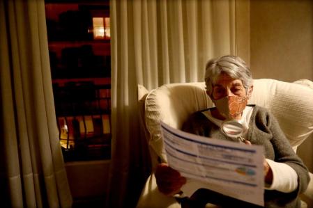 foto XAVIER CERVERA 16/01/2021 una mujer mayor mira con lupa la letra pequena de la factura de la luz, electricidad, ..porque no acaba d entender la subida y tarifas de estos dias de necesidad con temperaturas extremadamente frias... con poca luz, y cierta penumbra en su casa donde vive sola (con mascarilla por la pandemia covid coronavirus ,entre segunda y tercera ola)