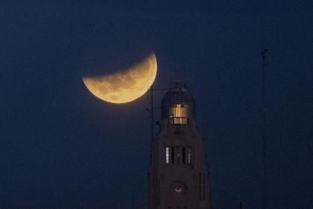 The moon sets behind the Montevideo port, in Uruguay, Wednesday, May 26, 2021, during a lunar eclipse, also known as a super blood moon.