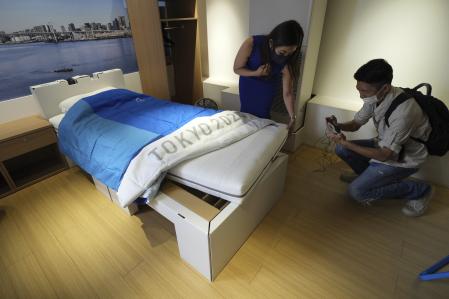 Journalists look at cardboard beds, for the Tokyo 2020 Olympic and Paralympic showing at the Village Plaza near Tokyo 2020 Olympic and Paralympic Village Sunday, June 20, 2021, in Tokyo. (AP Photo/Eugene Hoshiko)