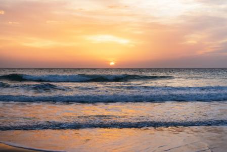 The sun disappearing on the horizon on a beautiful sunset evening at El palmar beach in Southern Spain.