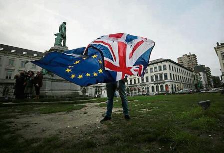 FILE - In this Thursday, Jan. 30, 2020 file photo, a man unfurls a Union and EU flag outside the European Parliament in Brussels. Five years ago, Britons voted in a referendum that was meant to bring certainty to the U.K.â#{emoji}128;#{emoji}153;s fraught relationship with its European neigbors. Votersâ#{emoji}128;#{emoji}153; decision on June 23, 2016 was narrow but clear: By 52 percent to 48 percent, they chose to leave the European Union. It took over four years to actually make the break. The former partners are still bickering, like many divorced couples, over money and trust. (AP Photo/Virginia Mayo, File)