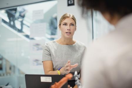 Female technician in control, talking in a meeting with her colleagues.
