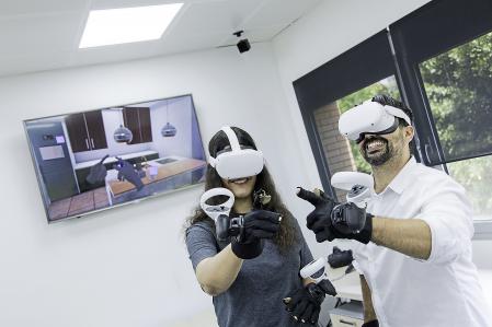 Luis Castillo y una miembro de su equipo prueban los guantes hápticos. En pantalla, se refleja la mano y sus gestos con precisión
