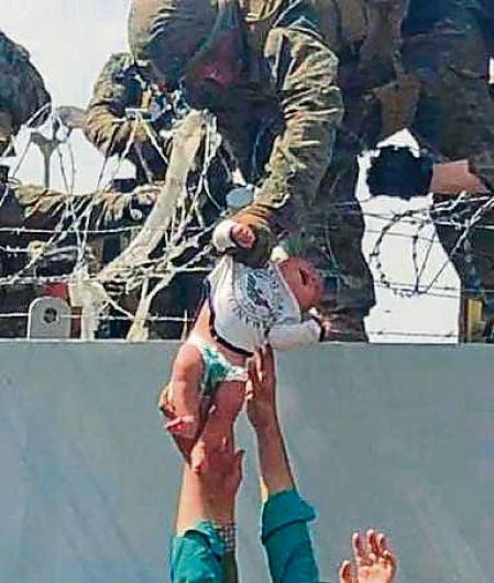 In this image from video provided by Omar Haidari and taken on Thursday, Aug. 19, 2021 which shows a baby being lifted across a wall at Kabul Airport in Afghanistan by US soldiers. The image grabbed from footage, taken on Thursday, showed the infant being pushed up to the soldiers by people in the crowd gathered outside the airport, amid the chaos of those fleeing the Taliban takeover of the country. (Omar Haidari via AP)