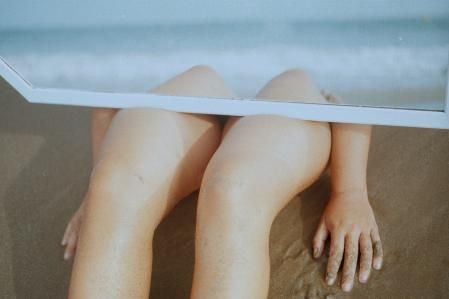 Las piernas de un/a joven sobre la arena.