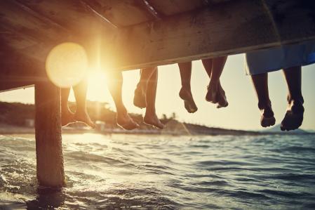 Five people having fun sitting on pier. Feet shot from below the pier. Sunny summer day evening.
Nikon D850