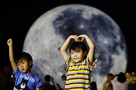 Niños frente a un globo gigante con forma de luna antes del Festival del Medio Otoño, en Hong Kong.