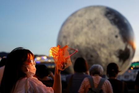 Una mujer posa para una foto frente a un globo gigante con forma de luna antes del Festival del Medio Otoño, en Hong Kong.