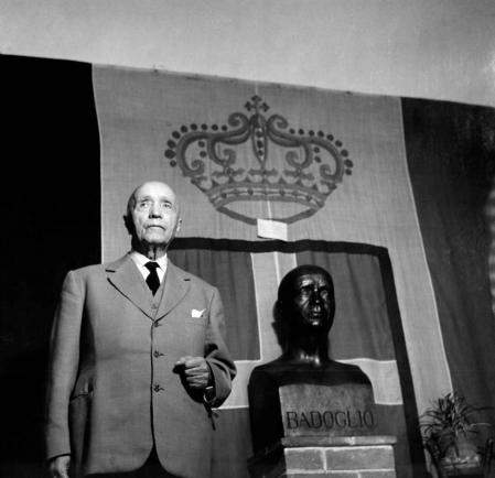 Pietro Badoglio ante la bandera de la casa de Saboya y junto a un busto suyo de bronce en su pueblo natal, Grazzano Badoglio, 1954.
