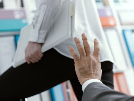 Sexual harassment in the workplace: the boss is about to touch his female employee's buttocks