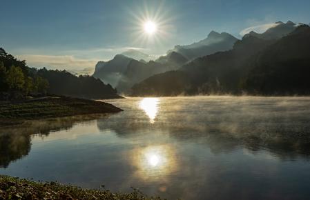 Sale el sol detrás de la Serra de Picancel con el agua humeante en el embalse de La Baells.