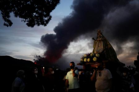 Faithful walk in a procession with the Virgen del Pino (The Pine Virgin) around its chapel to pray for the Cumbre Vieja volcano to stop as it continues to erupt in the background at El Paso, on the Canary Island of La Palma, Spain, October 19, 2021. REUTERS/Susana Vera