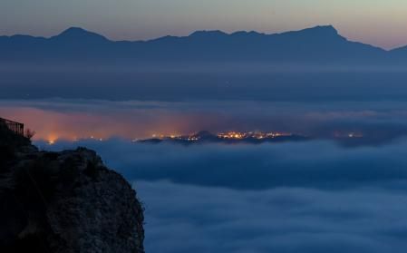 Sant Pere de Torelló entre nieblas con el monte Puigsacalm al fondo y, en primer plano, el abismo Roc Llarg.