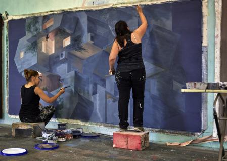 Cinta Vidal y Helena Salvador trabajando en equipo en la primera fase del mural, la que sirve para dar las primeras texturas de color