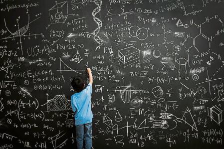 Young boy writes math equations on chalkboard niño pizarra