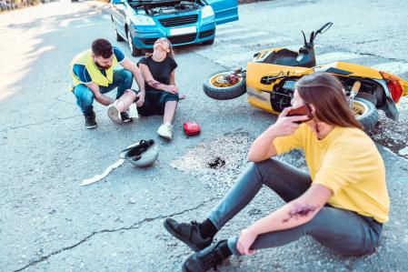 Un joven atiende a dos jóvenes que han sufrido un accidente en moto
