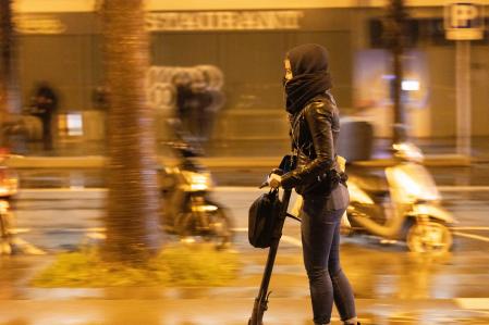 Una mujer en patinete eléctrico circulando por las calles de Barcelona.