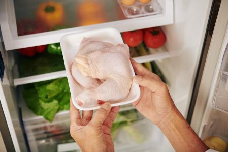 Man taking package of fresh chicken thights out of refrigerator