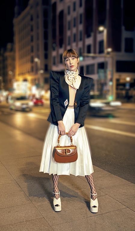 Con americana con cadena, falda con pliegues, bolso con asa de bambú y pañuelo. Total look de Gucci Love Parade