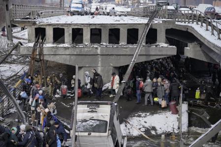 Abandoned vehicles of those who fled sit on the road before the destroyed bridge as people continue to leave the town of Irpin, on the outskirts of Kyiv, Ukraine, Tuesday, March 8, 2022. Demands for ways to safety evacuate civilians have surged along with intensifying shelling by Russian forces, who have made significant advances in southern Ukraine but stalled in some other regions. Efforts to put in place cease-fires along humanitarian corridors have repeatedly failed amid Russian shelling. (AP Photo/Vadim Ghirda)